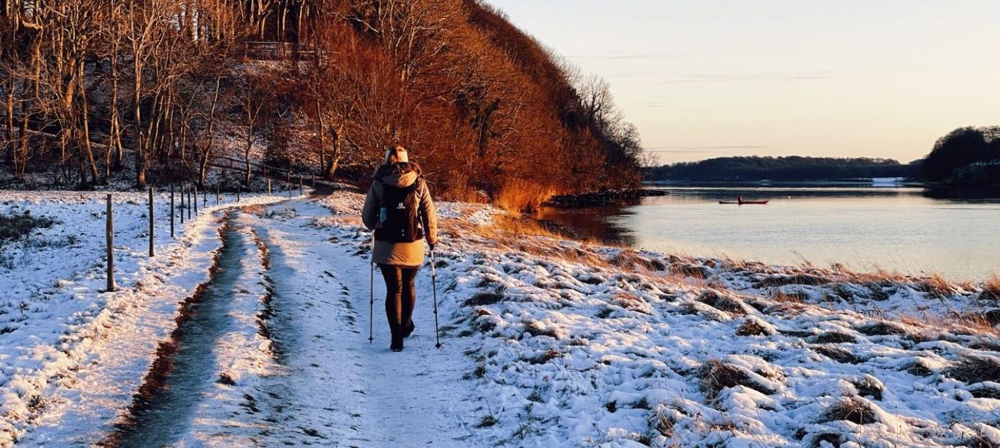 Vinterlandskab med en der vandre og en i kajak på vandet